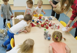 dzieci i ciocie wybieraja ozdoby rozsypane na stoliku