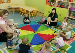 dzieci z opiekunkami i misiami siedzą na dywanie