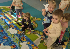 dzieci na dywanie, zbierają i przyglądają się rybkom