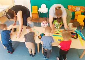 dzieici wraz z ciociami ozdabiają jajka
