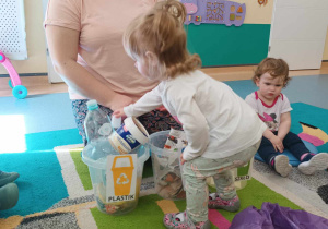 dziewczynka wkłada wybrany śmieć do odpowiedniego wiaderka
