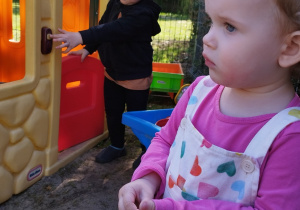 chłopiec naciska dzwonek na domku, z przodu stoi dziewczynka