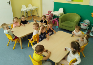 dzieci siedzą przy stolikach, pokazują zrobione pszczółki