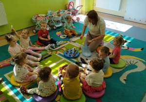 opiekunka częstuje dzieci miodem, wszyscy siedza na dywanie