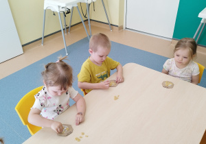 dzieci przy stoliku przyklejają makaron