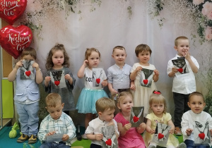 dzieci stoją na tle , uśmiechają się i trzymają prezent