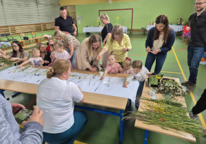 rodzice i dzieci przyklejają do kartonu kwiaty i trawy