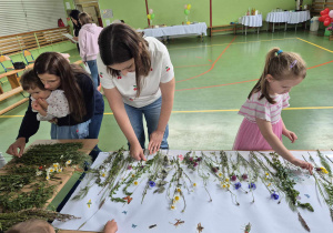 dzieci i rodzice przyklejają trawy i kwiaty