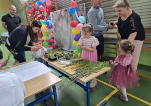 dzieci i rodzice wybierają trawy spośród naszykowanych na stoliku