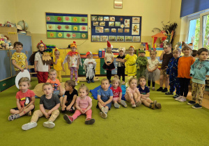 mali aktorzy stoją z tyłu, a maluchy ze żłobka siedzą na dywanie