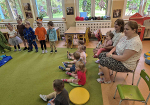 maluchy siedzą na dywanie, a opiekunki za nimi-oglądają przedstawienie
