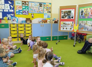 dzieci siedzą na dywanie, a pani policjantka opowiada