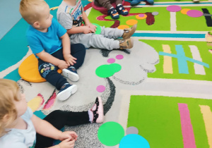 dzieci siedzą na dywanie mają kolorowe kropki