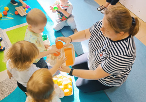 dzieci przynoszą opiekunce do pudełka piłki