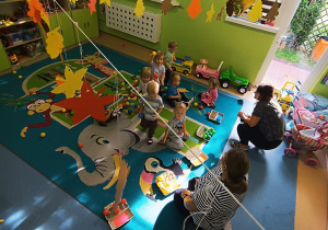 opiekunki patrzą jak dzieci segregują piłeczki