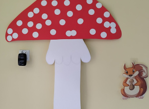 duży kartonowy muchomor, a pod nim obrazek wiewiórki