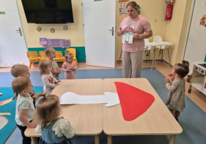 opiekunka pokazuje dzieciom ilustrację muchomora