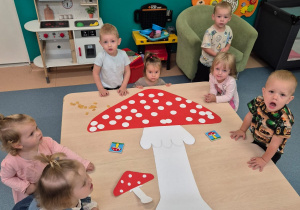 dzieci stoją wokół stolika, na którym leży wykonany muchomor