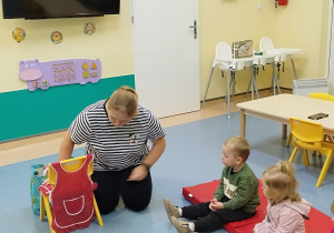 dzieci siedzą i słuchają opowiadanego wiersza przez opiekunkę