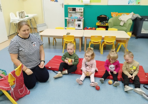 dzieci trzymają jabłka i słuchają opowiadania opiekunki