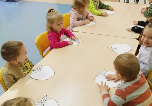 dzieci siedzą przy stoliku i czekają na pracę plastyczną