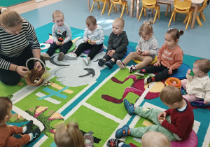 opiekunka rozdaje dzieciom kasztany w kolczastych skorupkach