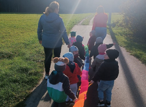idące drogą dzieci wraz z opiekunkami, trzymają węża