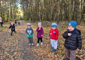 dzieci stoją na drodze w lesie, niektóre biegają
