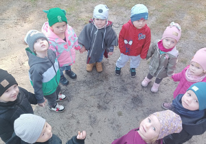 dzieci stoją w kole niektóre patrzą w aparat