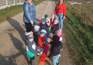 dzieci wraz z opiekunkami na drodze,dzieci trzymają się węża