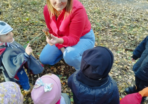 opiekunka pokazuje dzieciom znalezionego grzyba, dzieci stoją przed nią