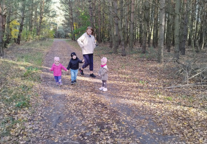 dzieci wraz z opiekunką stoją na drodze w lesie