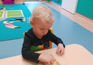 chłopiec wciska pestki dyni w masę dyniową