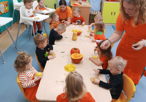 dzieci przy stolikach wykonują pracę, opiekunki pomagają