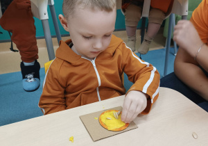 chłopiec wciska pestki w masę dyniową