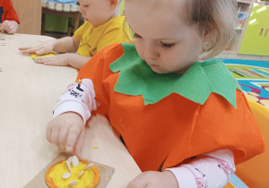 dziewczynka wciska pestki w masę dyniową