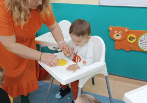 opiekunka pomaga chłopcu ugniatać masę dyniową