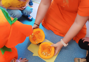 opiekunka pokazuje dzieciom przekrojoną dynię