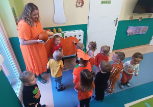 opiekunka pokazuje dzieciom różne dynie
