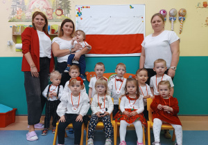 dzieci i opiekunki pozują do zdjęcia z flagą Polski