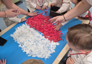 dzieci stoją wokół stolika, na którym leży wykonana praca plastyczna