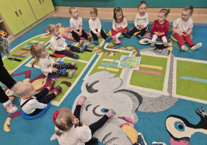 dzieci siedza na dywanie, na środku leży mapa Polski