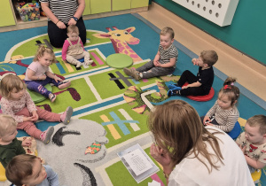 opiekunki siedzą z dziećmi na dywanie, dzieci słuchają opowiadania o jeżu