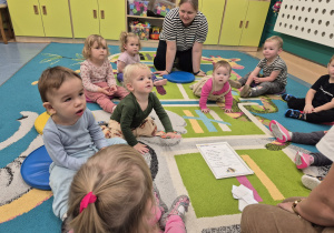 dzieci z opiekunką siedzą na dywanie słuchają co mówi o jeżu