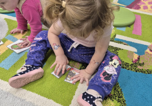 dziewczynka siedzi na dywanie i układa obrazek jeża z puzzli