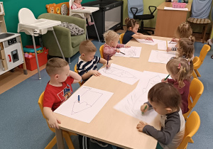 dzieci siedzą przy stoliku i kolorują