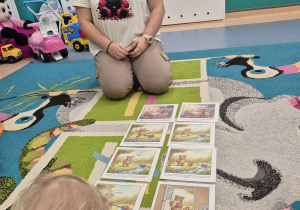 dzieci siedzą na dywanie, na którym leżą obrazki z opowiadania