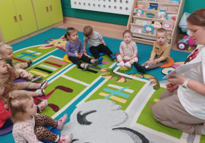 dzieci siedzą na dywanie słuchają opowiadania o misiu