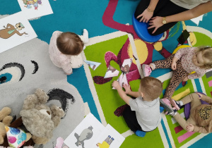 dzieci siedzą na dywanie próbują ułożyć puzzle