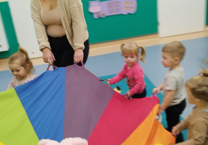 dzieci trzymają chustę na której leżą misie i kręcą się w koło